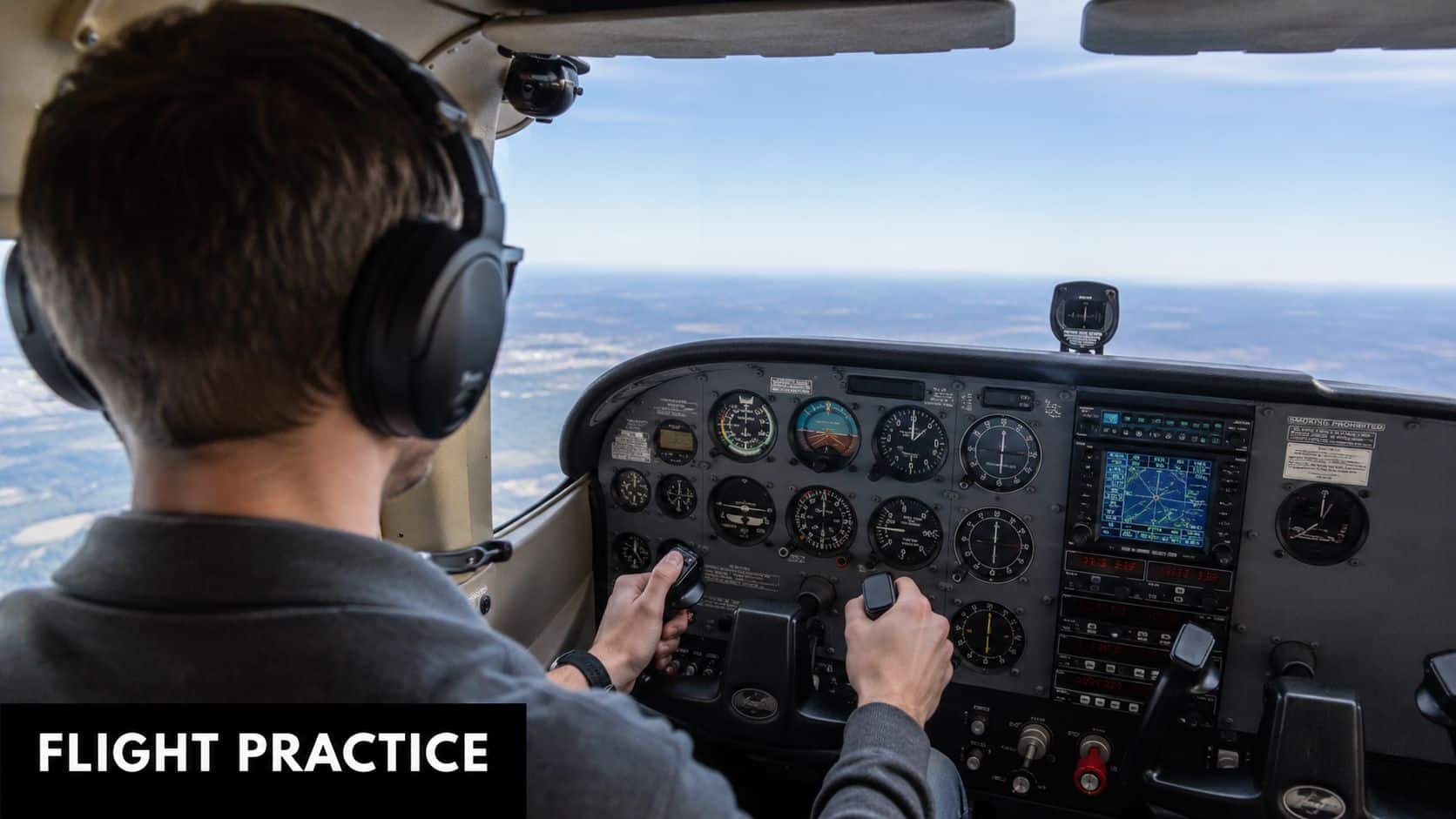 Vertical Speed Indicator: Techniques for Pilots 5 A pilot wearing headphones navigates a light aircraft, focusing on the instrument panel while flying above ground.
