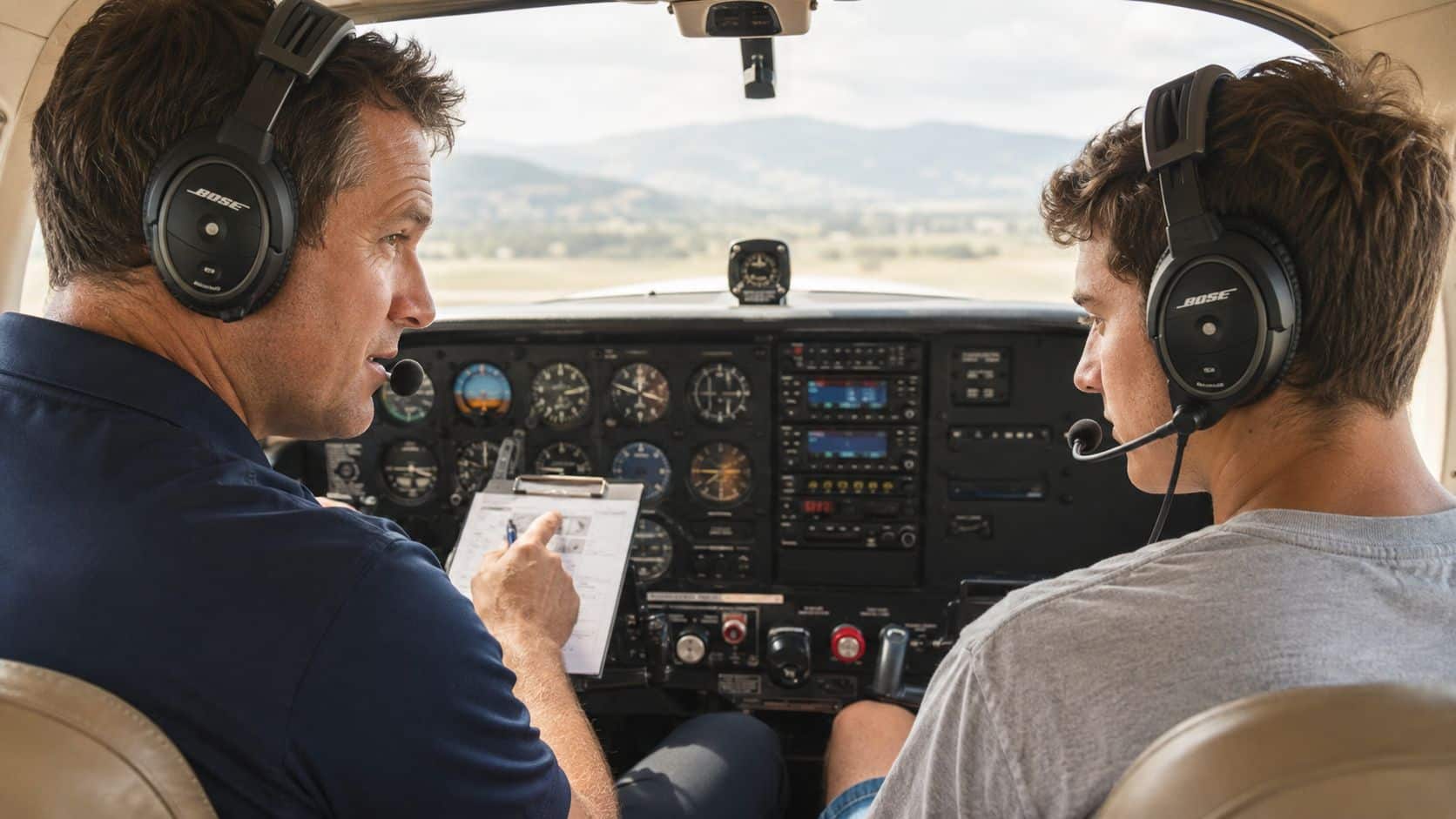 Commercial Pilot Training Programs Explained for 2026 4 An experienced flight instructor pointing at a checklist while teaching a student in a small aircraft cockpit.