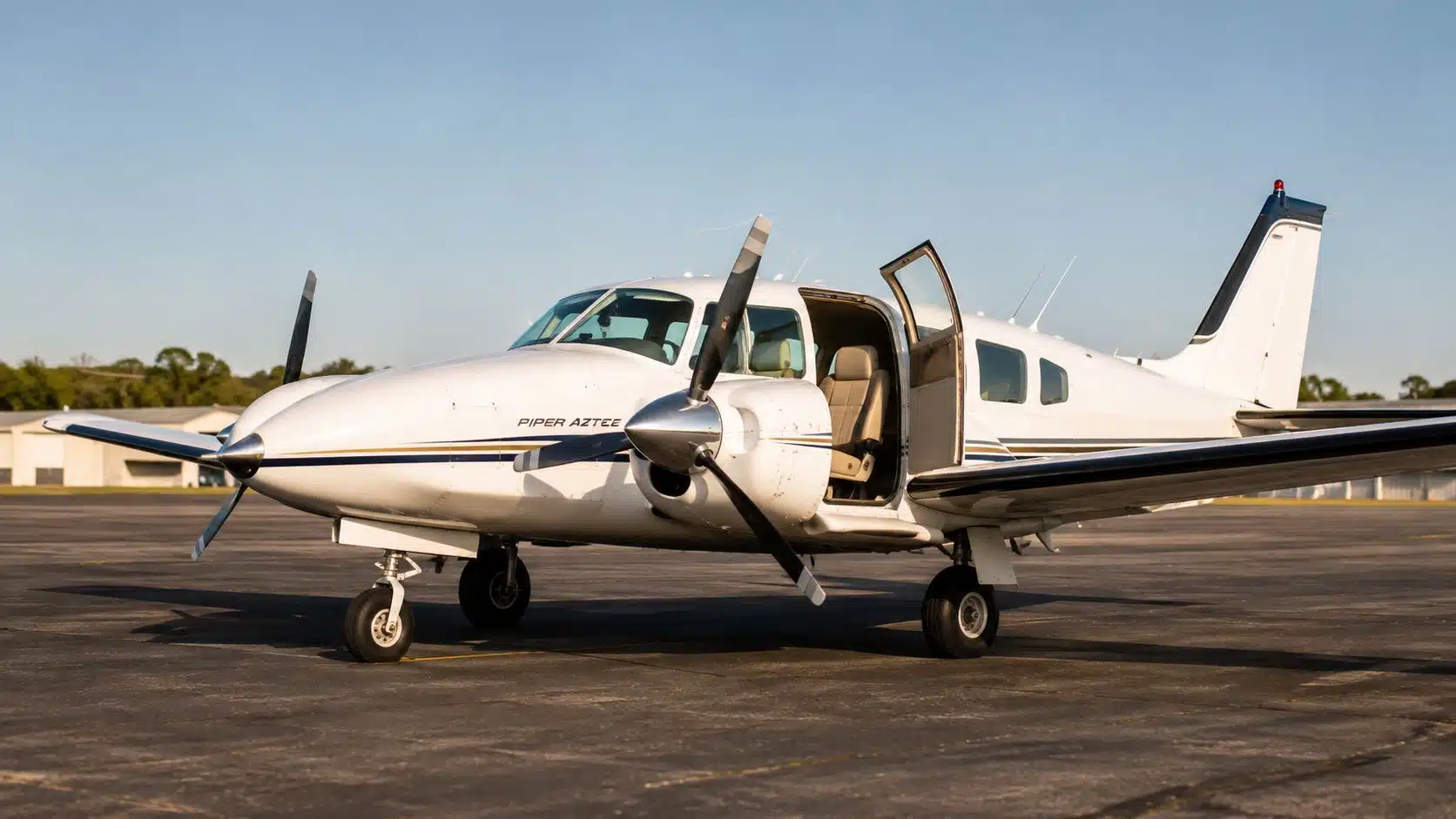 Piper Aztec Rental: A Pilot's Guide to Training and Checkout 2 A white Piper Aztec light aircraft parked on an airport tarmac with its cabin door open.
