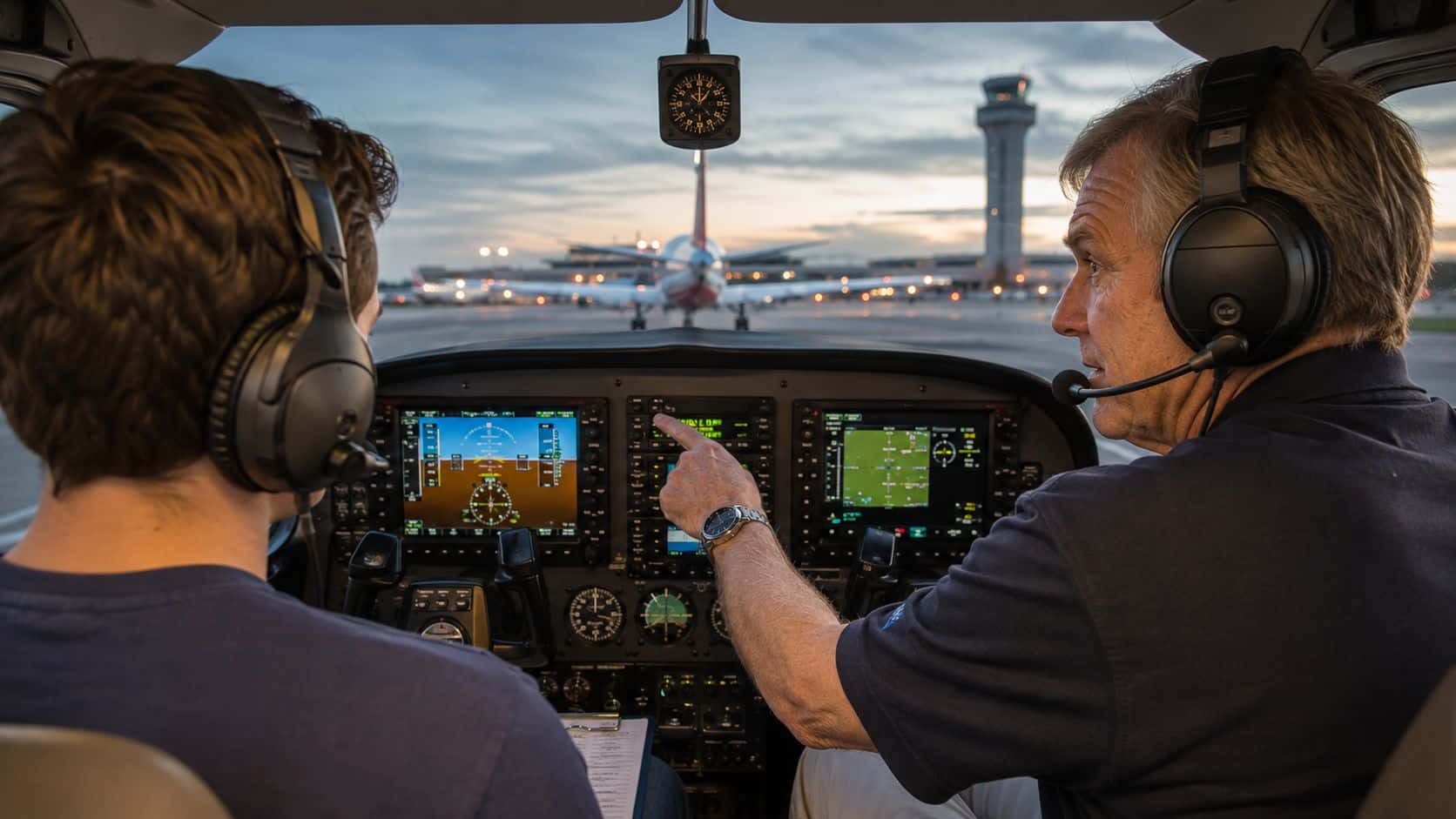 What Is a Flight Instructor and Why They Matter 3 A flight instructor pointing to the instrument panel while training a student in an airplane cockpit.