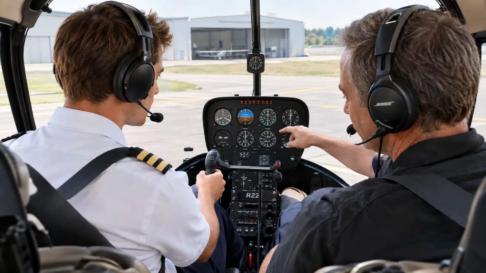Helicopter Add on Rating Cost Guide for Pilots 2 A student pilot and flight instructor in a helicopter cockpit discussing the instrument panel during training.