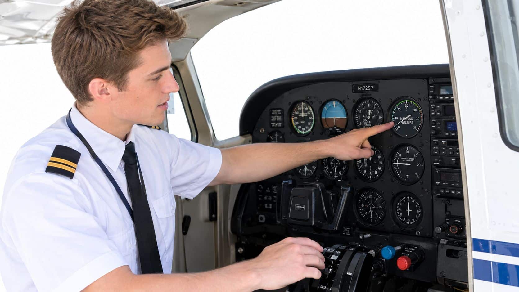 Manifold Pressure Explained for Student Pilots 2 A pilot inside a small plane cockpit, pointing his finger at the manifold pressure gauge display.