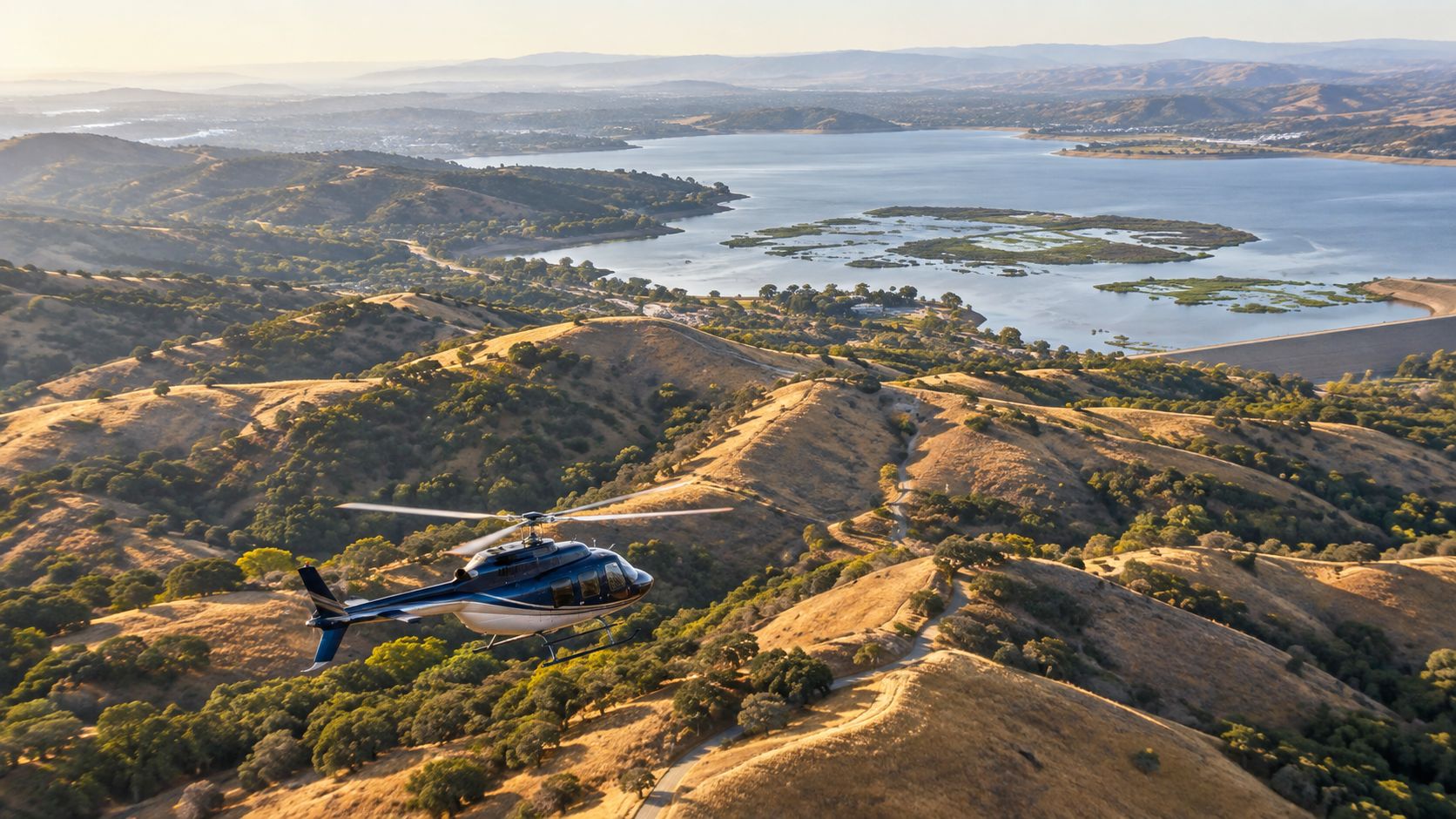 Scenic Helicopter Flights: What to Expect on a Tour 3 A blue helicopter flying over beautiful rolling golden hills with a large lake in the background